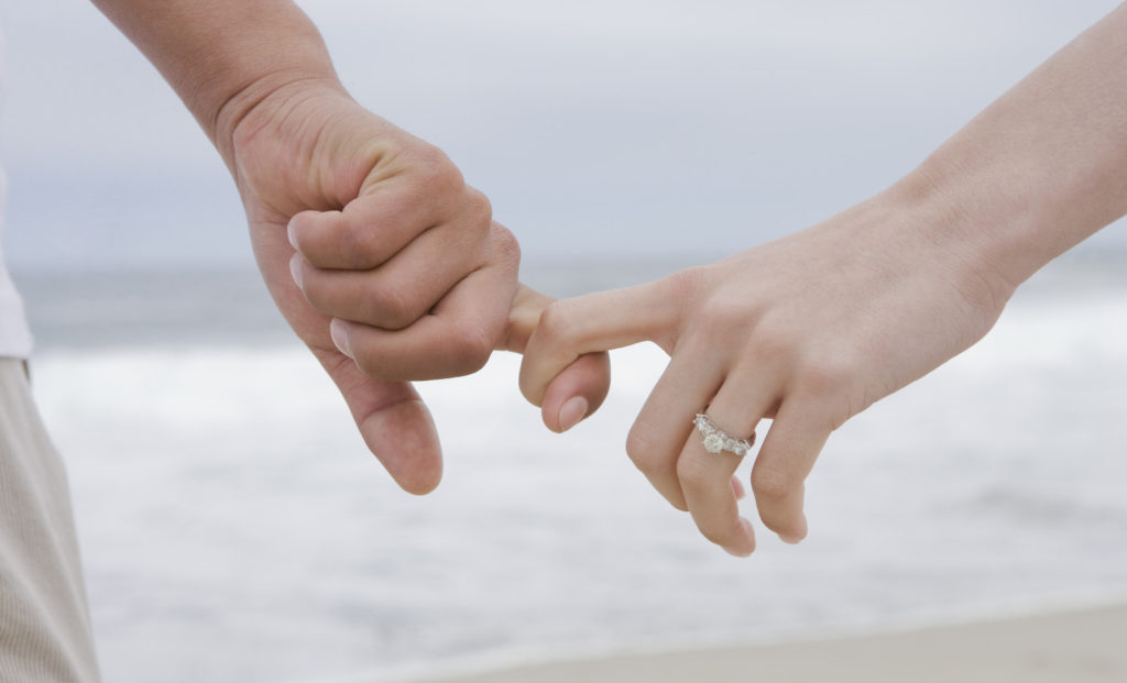 Hispanic couple holding hands on beach