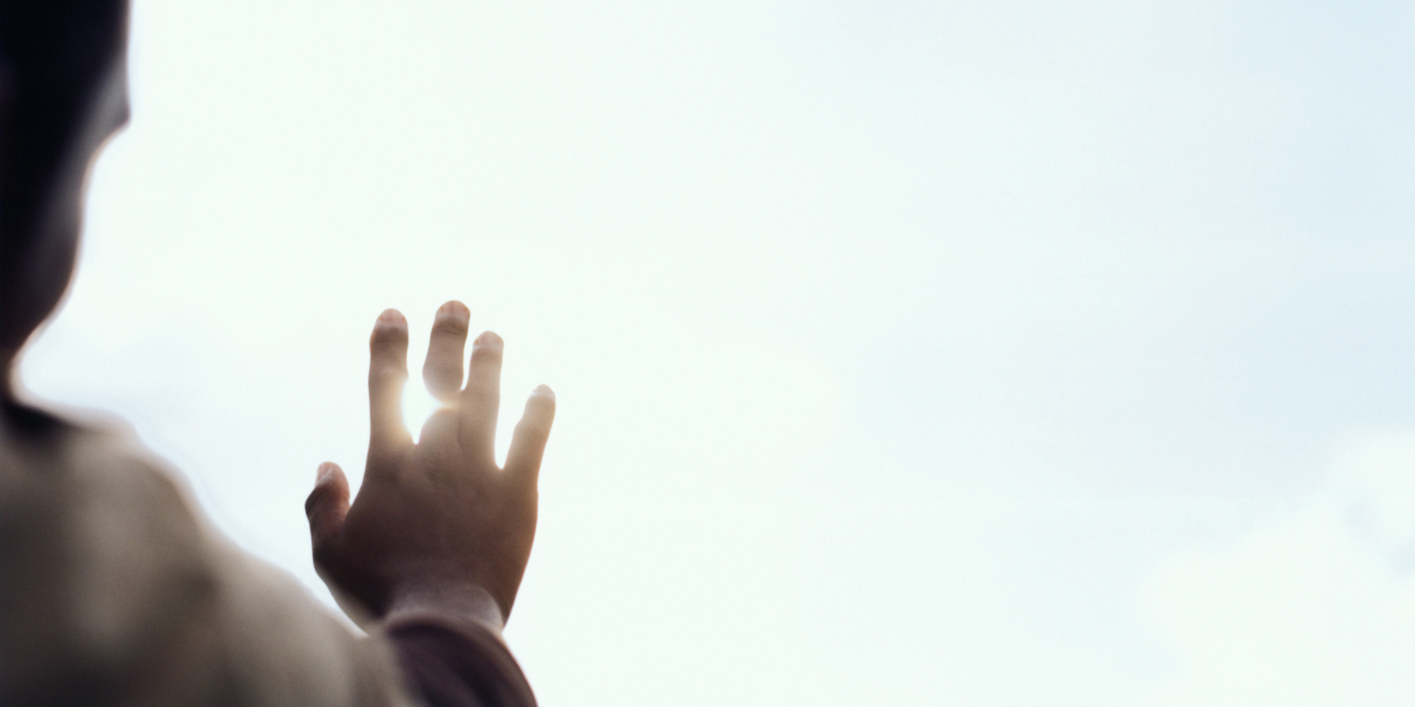 Young man blocking sun with hand, close up