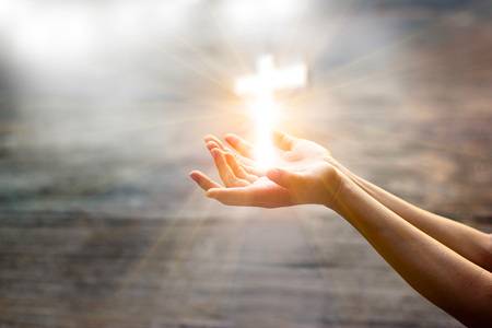 99195057-woman-with-white-cross-in-hands-praying-for-blessing-from-god-on-sunlight-background-hope-concept