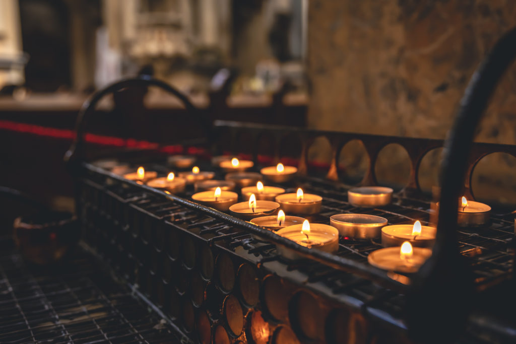 Many small candles in a Catholic church in a dark interior.