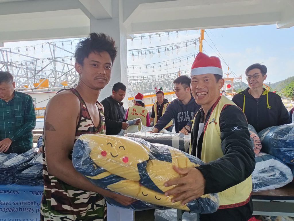 鄧立仁神父將被子交給漁工