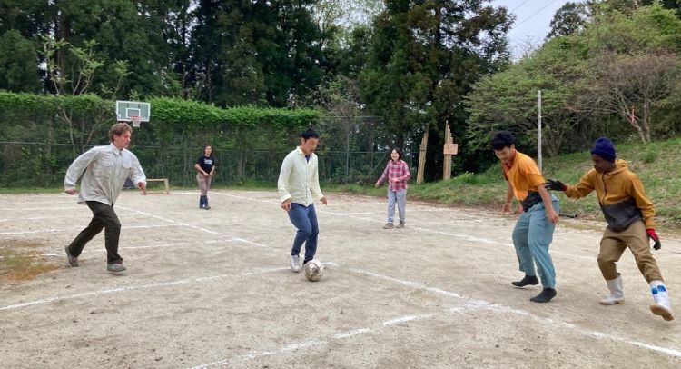 中井淳神父 (持球者) 和青年踢足球