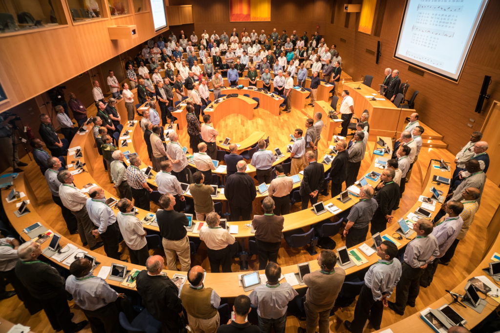 GC 36 Opening session with a Prayer. Adolfo Nicolás, hands over the meeting to Jim Grummer, SJ, as vicar of GC36. Afterwards, Adolfo takes his seat in among the delegates.