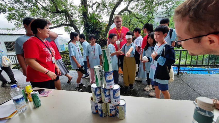 黄贞玛女士和耶稣会林嘉博修士(中)及麦智宽神父(右边冒出头者)陪伴孩子玩游戏